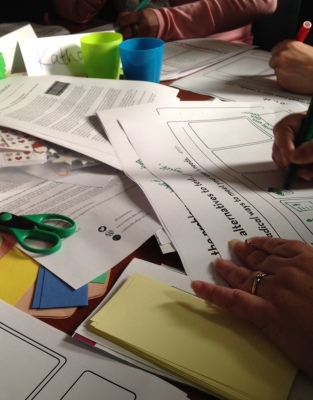 Photo from CoLab Exchange session of papers, scissors and people's hands filling in worksheets